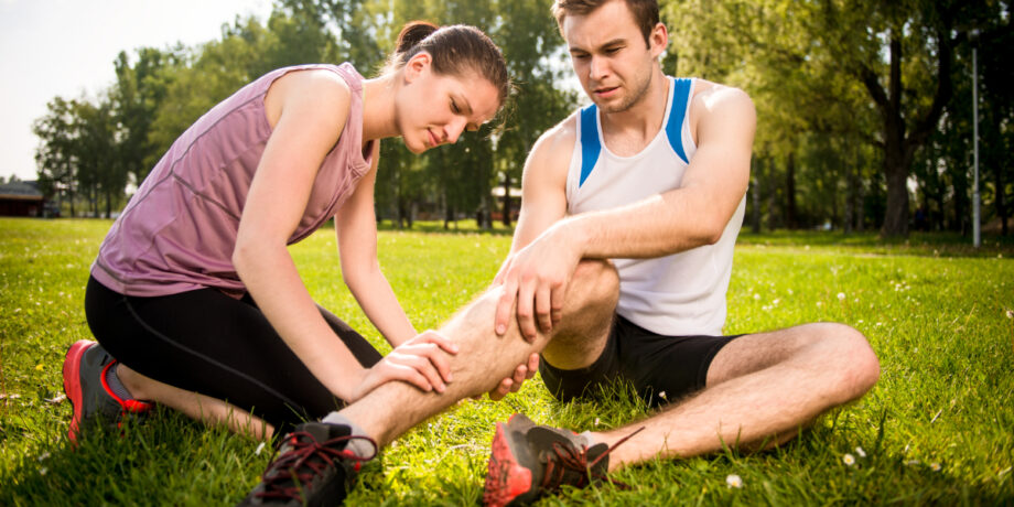 Sportler hat wegen einer Muskelzerrung in der Wade Schmerzen und seine Freundin schaut sich die Zerrung an