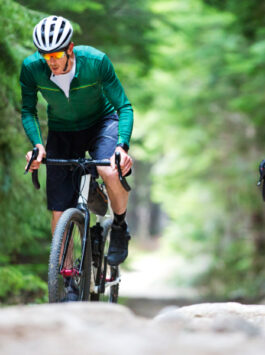 Zwei Radfahrer fahren auf ihren Gravel Bikes durchs Gelände in einem Wald