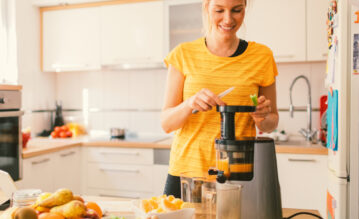 Frau macht sich einen Slow Juice in ihrer Küche