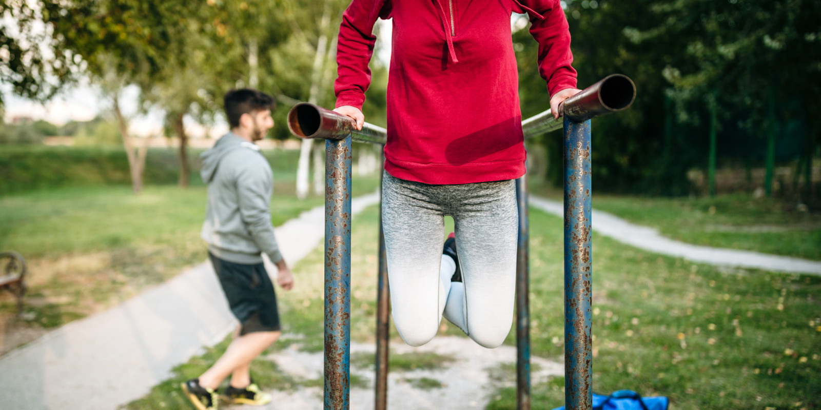 Junge Frau macht Dips am Barren beim Cathelistic Workout im Park