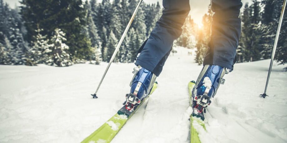 Sportler beim Skifahren im Winterwald bei Sonnenuntergang