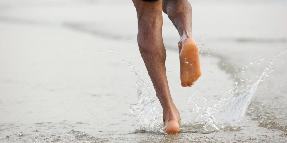 Mann läuft barfuß am Strand entlang