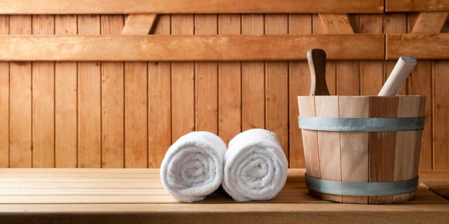 Handtücher und Aufguss stehen in einer Sauna aus Holz