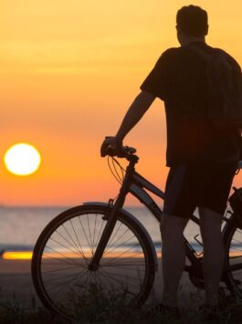 Radfahrer macht eine Pause, um den Sonnenuntergang über dem Meer zu beobachten