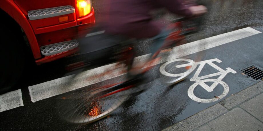 Radfahrer fährt auf dem Fahrradstreifen neben einem LKW durch die Stadt
