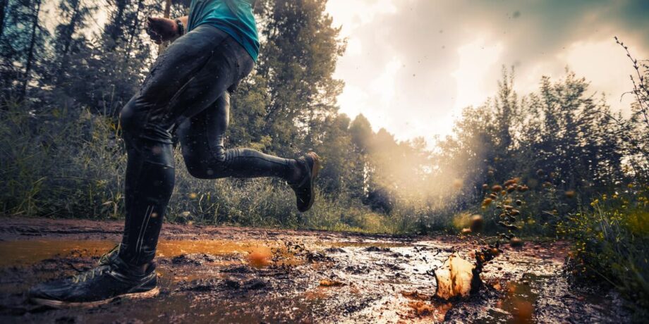 Sportler läuft beim Trailrunning in der Natur durch Pfützen