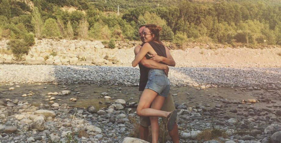 Max und Carina umarmen sich an einem Flussbett in der Natur