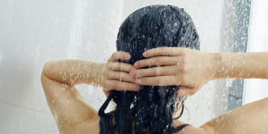 Frau beim Haarwaschen in der Dusche