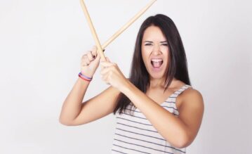 Frau mit zwei Schlagzeugstöcken vor ihrem Drums Alive Training