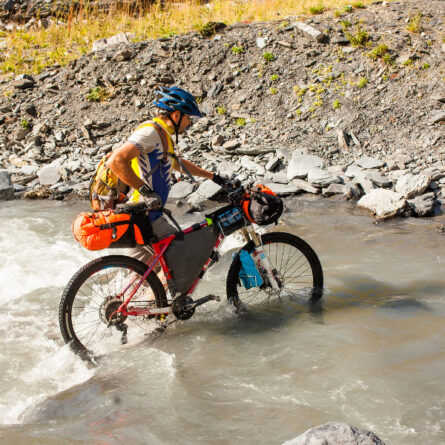 Radfahrer schiebt sein Mountainbike durch einen Fluss