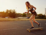 Junge Frau beim Longboardfahren auf der Straße
