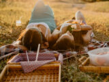Zwei Frauen liegen im Sommer auf einer Picknickdecke auf einer Wiese