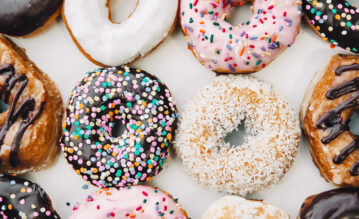 Bunte Donats mit buntem Zucker-Topping liegen auf einem weißen Tisch