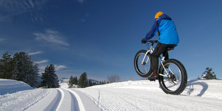 Fahrradfahrer fährt mit seinem Fatbike durch den Schnee.