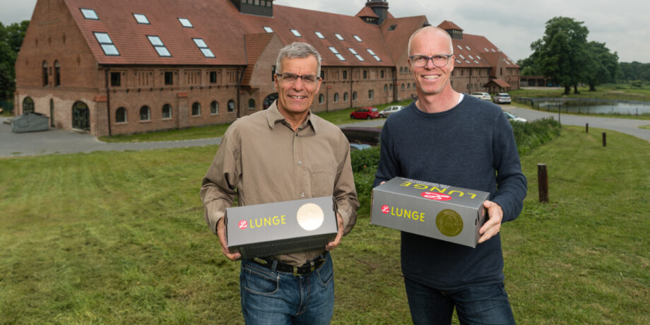 Die Brüder Ulf und Lars Lunge stehen vor der Schuhmanufaktur und halten Schuhkartons ihrer Marke in den Händen