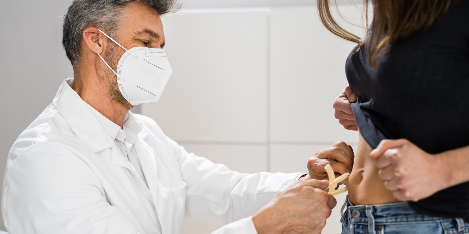 Arzt misst den Körperfettanteil seiner Patientin mit einer Caliper-Zange