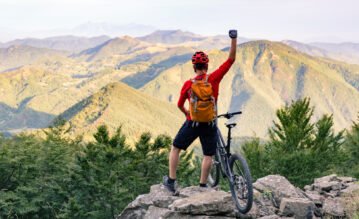 Radfahrer steht mit seinem Rad auf einem Berg
