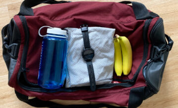 Sebastian packt seine Trainingstasche und packt Wasserflasche, Handtuch, Garmin-Uhr und 2 Bananen ein