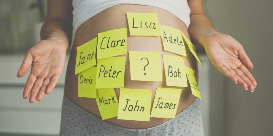 Schwangere Frau hat einige Klebezettel mit Babynamen auf ihren Bauch geklebt