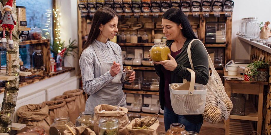 Frau und Verkäuferin schauen sich die Waren in einem verpackungsfreien Supermarkt gemeinsam an.
