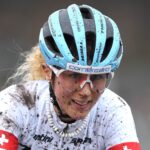 Mountainbikerin Jolanda Neff lächelnd beim Rennen - mit Schlamm im Gesicht. ©Ryan Bodge
