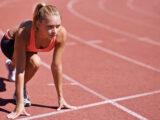 Junge Frau in Startposition beim 100 Meter Lauf