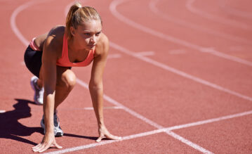 Junge Frau in Startposition beim 100 Meter Lauf