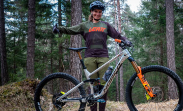 Profibikerin Carolin Gehrig steht im Wald neben ihrem Mountainbike