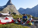 Lars Schneider sitzt mit seinen zwei Kindern vor einem Zelt in den Bergen Norwegens