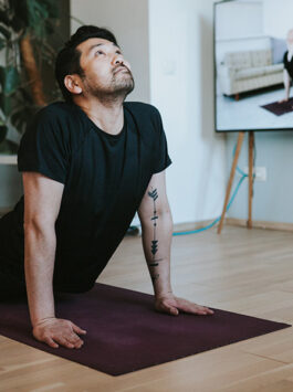 Mann macht zuhause Yoga-Übungen mit einem virtuellen Trainer