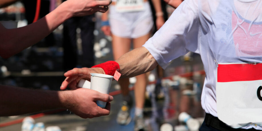 Läufer bekommt ein Becher Wasser während des Wettkampfes