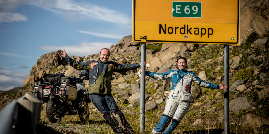 Lennart und Maia hängen sich fröhlich an das Nordcap Schild.