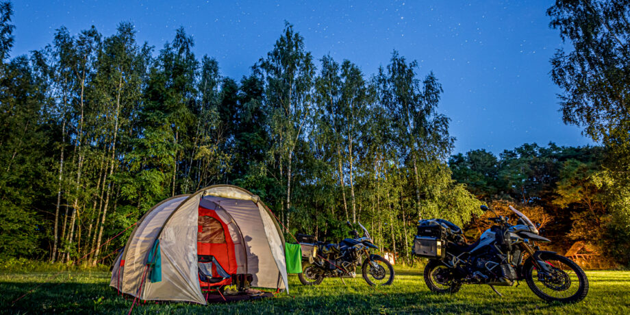 Zelt und Motorräder stehen in Litauen unter einem Sternenhimmel