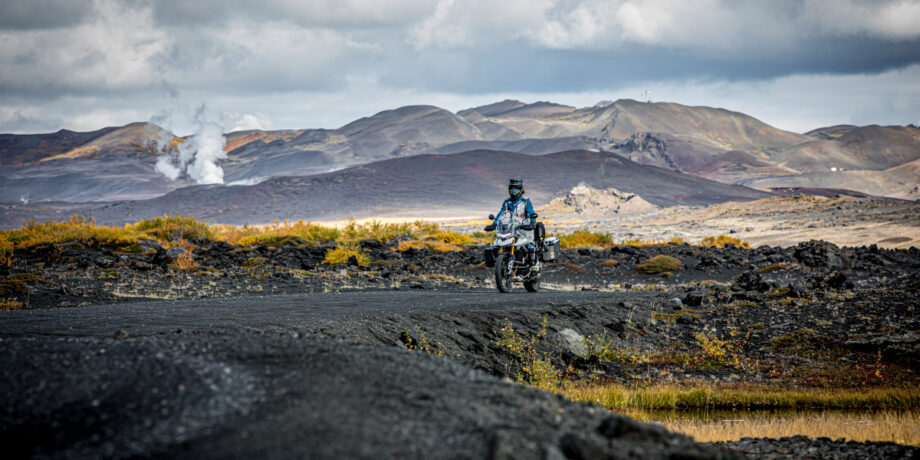 Maia fährt auf Island und hinter ihr kommt Rauch aus Vulkanen