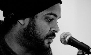 Faiz Mangat auf einem schwarz-weiß-Foto neben einem Mikrofon