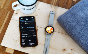 Smartphone mit geöffneter Garmin Connect App liegt neben der Garmin Venu
