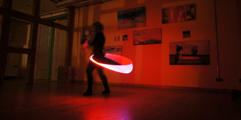 Kristin Rein tanzt mit einem beleuchteten Hula Hoop im dunklen Raum