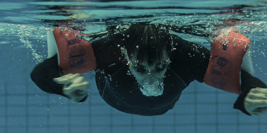 Johnny Grasser schwimmt mit Schwimmflügeln in einem Schwimmbecken