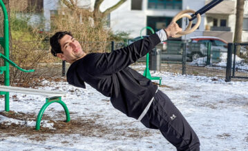 Fitnesstrainer Gino Singh hängt an Turnringen im Garten