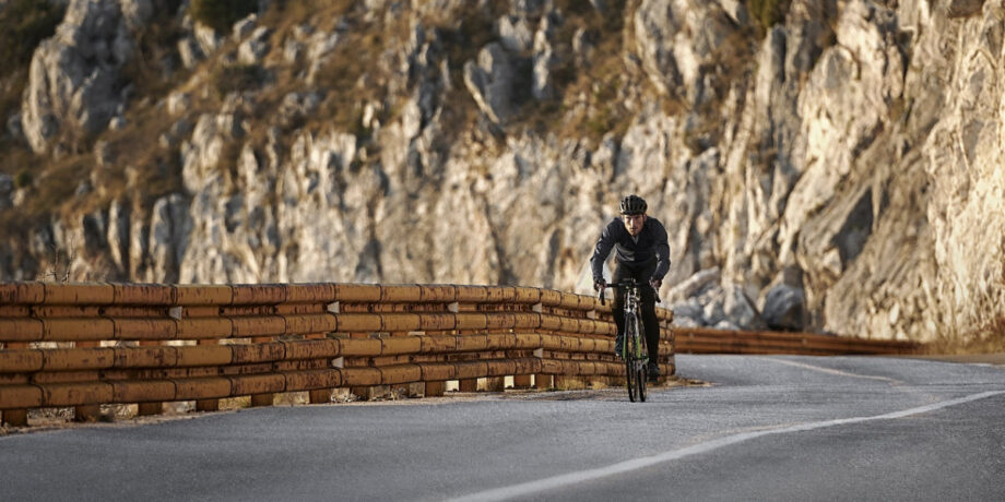 Mann fährt mit dem Rennrad auf einer Straße direkt an den Bergen