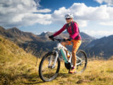 Frau fährt mit ihrem Mountainbike durch die Berge