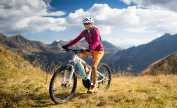Frau fährt mit ihrem Mountainbike durch die Berge