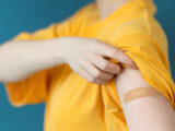 Frau zeigt Arm nach Grippeschutzimpfung