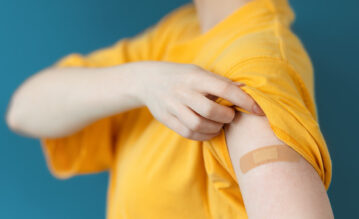 Frau zeigt Arm nach Grippeschutzimpfung