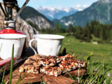 Vegane Nussriegel neben Kaffeetassen bei einer Wanderung in den Bergen