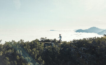 Juliane Ilgert beim Traillaufen auf einem Berg. Hinter ihr die Wolken.