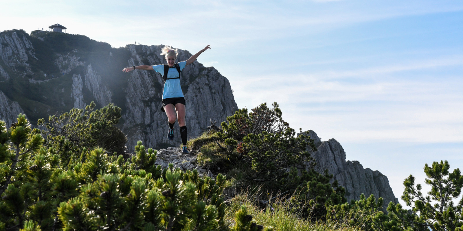 Juliane Ilgert springt auf ihrem Trail über ein Hindernis in den Bergen