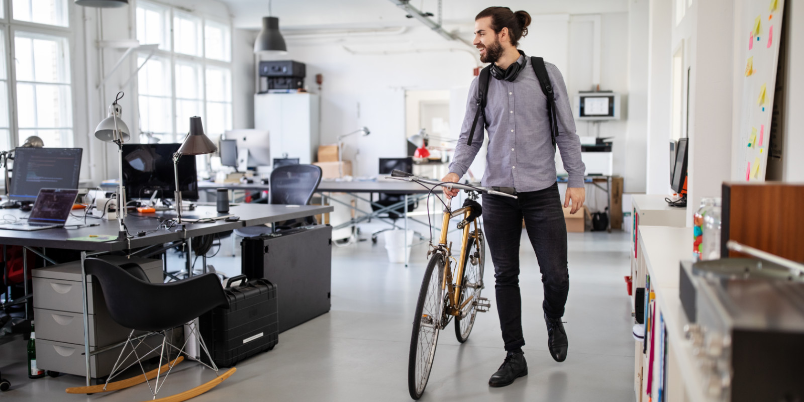 Junger Mann schiebt sein Fahrrad durch das Büro
