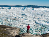 Mann steht vor einem Gletscher, der schmilzt