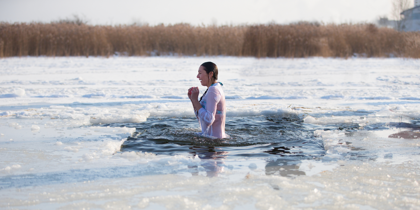 Frau badet in einem Eisloch